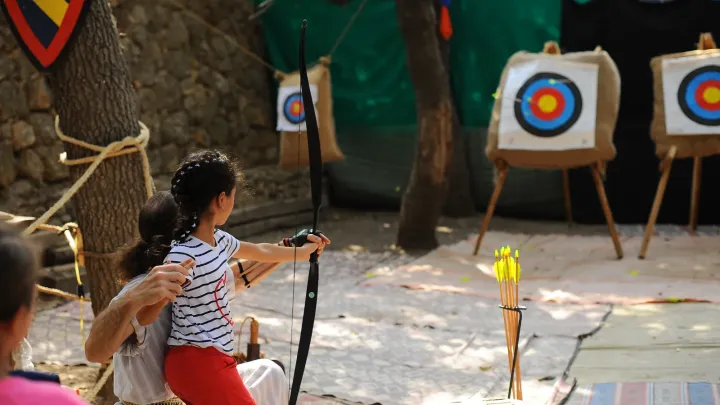 ילד יורה בחץ וקשת לעבר מטרות במתחם הפסטיבל.