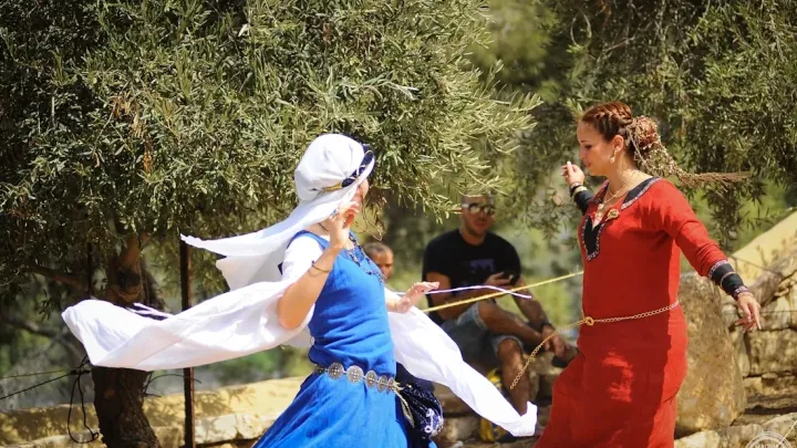 רקדניות בתלבושות כחולות ואדומות מסתובבות במהלך המופע.